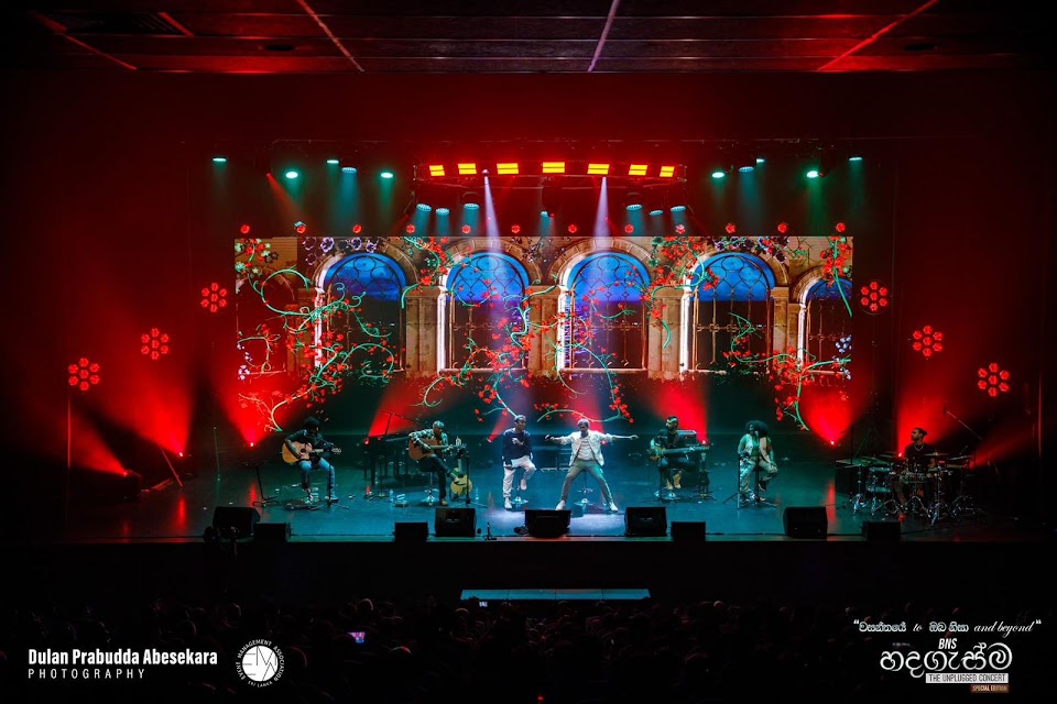 Live concert with a large LED screen and red stage lighting