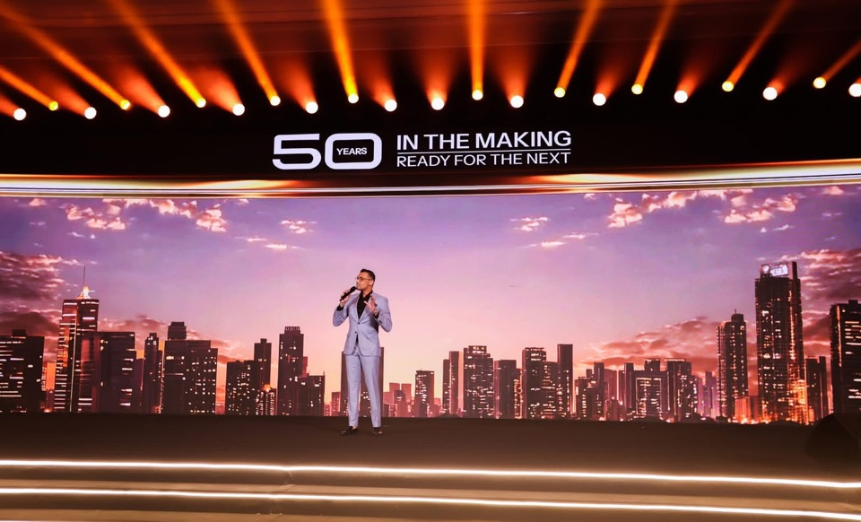 Presenter on a stage with a city skyline LED backdrop
