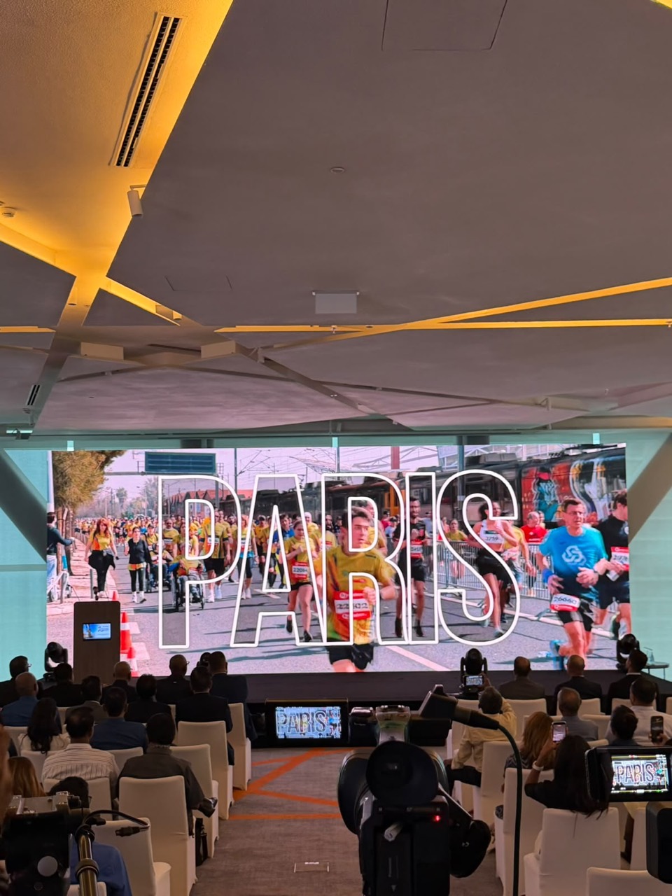 Large LED screen showing runners behind the word Paris